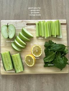 a cutting board topped with sliced up green apples and cucumbers next to lemon slices