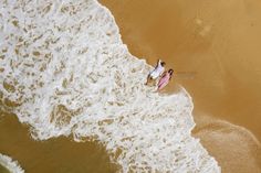 two people are standing in the water on their surfboards at the beach with waves