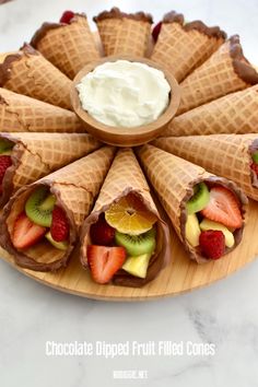 chocolate dipped fruit filled cones are arranged on a plate with a bowl of whipped cream