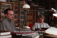 two men sitting at a desk in front of books