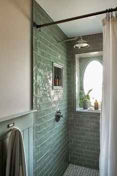 a bathroom with green tiles and a window