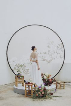 a woman standing in front of a large circular sculpture with flowers on it's sides