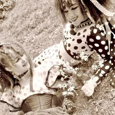 two women dressed in polka dot outfits sitting on the ground