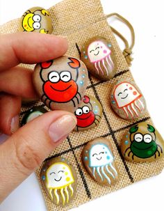 a person is holding some rocks with different designs on them and there are jellyfishs in the background