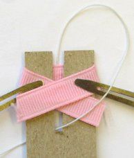 scissors are tied up to the side of a piece of cardboard with pink ribbon on it