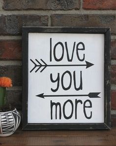 a sign that says love you more next to a potted plant