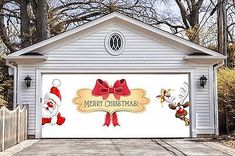 a garage decorated with christmas decorations and santa clause on the front door, in front of a white house