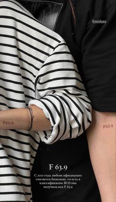 a woman with a tattoo on her arm holding onto another person's hand, both wearing black and white striped shirts