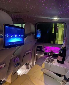 the interior of a car with purple lights on the ceiling and wine bottles in the back seat