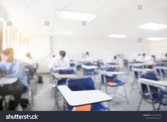 blurry image of students sitting at their desks in an empty classroom with blue chairs