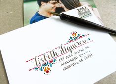 a wedding announcement with a pen on top of it next to an envelope and photo