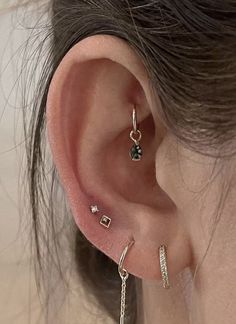 a close up of a person's ear with three different piercings on it