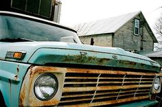 an old blue truck parked in front of a house