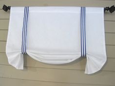 a white curtain hanging on the side of a house with blue trim and black hardware