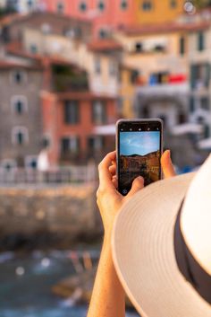 a person holding up a cell phone in front of a city with lots of buildings