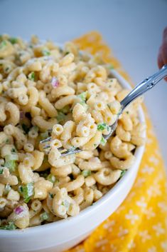 a white bowl filled with macaroni salad on top of a yellow table cloth