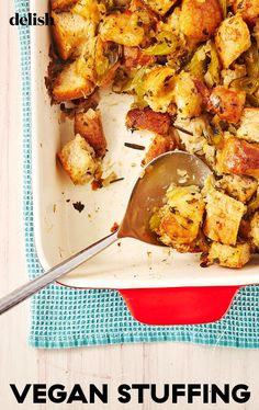 a white dish filled with stuffing next to a spoon