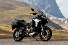 the motorcycle is parked on the side of the road in front of some mountain peaks