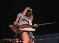 a woman with long blonde hair playing an electric guitar