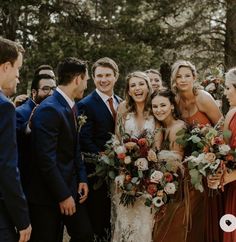 a group of people standing next to each other in front of some trees and bushes