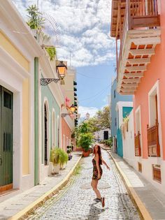 a woman walking down a cobblestone street in the middle of an old town