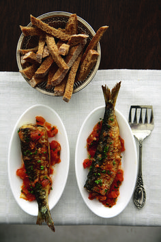 two white plates with fish and french fries on them next to a bowl of dipping sauce