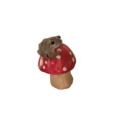 a frog sitting on top of a mushroom shaped object in front of a white background