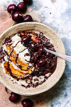 a bowl filled with ice cream and cherries on top of a marble countertop