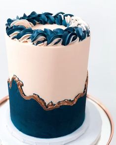 a blue and pink cake with gold trim on a white platter, ready to be eaten