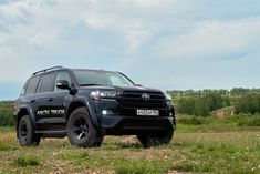 a black truck parked on top of a lush green field