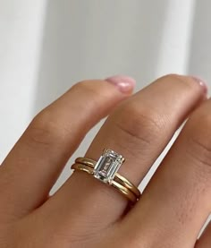 a woman's hand with two gold rings and a diamond ring on her finger