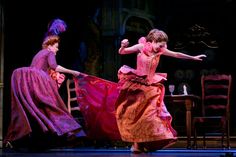 two women in dresses are dancing on stage