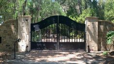 a gated entrance to a home surrounded by trees