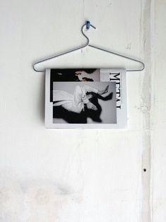 a black and white photo hanging on a wall next to a hanger with a magazine