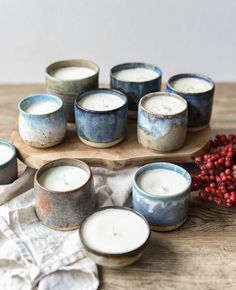 several candles sitting on top of a wooden tray next to berries and a cloth napkin