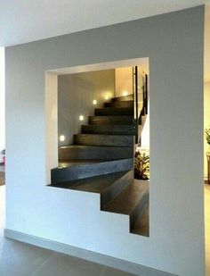 an open door leading to a staircase in a house with white walls and tile flooring