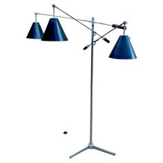 three light floor lamp with blue shades on the top and bottom, standing upright in front of a white background