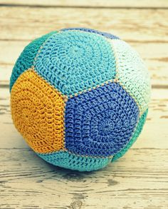 a blue and yellow crocheted ball sitting on top of a wooden table next to a