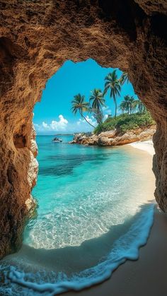 the view from inside an ocean cave looking out at the water and palm trees in the distance