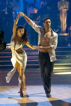 a man and woman dancing on stage at a dance competition with one holding the other's hand