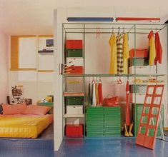 an open closet with clothes and other items on shelves next to a bed in a room