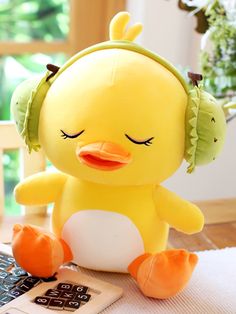 a yellow stuffed bird sitting on top of a table next to a laptop computer and headphones