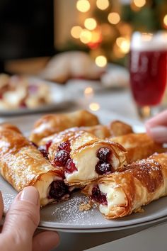 a plate with cranberry danish pastries on it and someone reaching for one