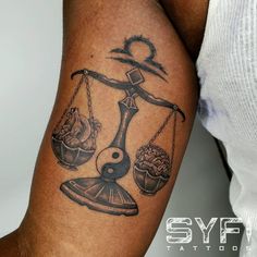 a man with a tattoo on his arm holding a balance scale