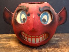 a red vase with an evil face on it