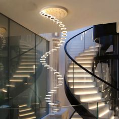 a spiral staircase with lights hanging from it's sides and an illuminated chandelier in the middle