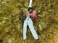 an ornament hanging from a christmas tree with gold tinsel in the background