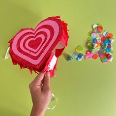 someone is holding up a heart shaped box with candy on the table next to it