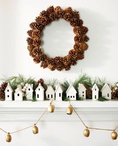 a mantle with pine cones and ornaments on it, next to a wreath that is hung above the mantel