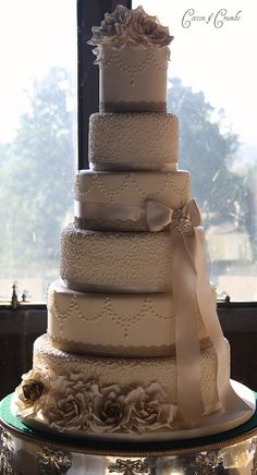 a large wedding cake sitting on top of a silver platter in front of a window